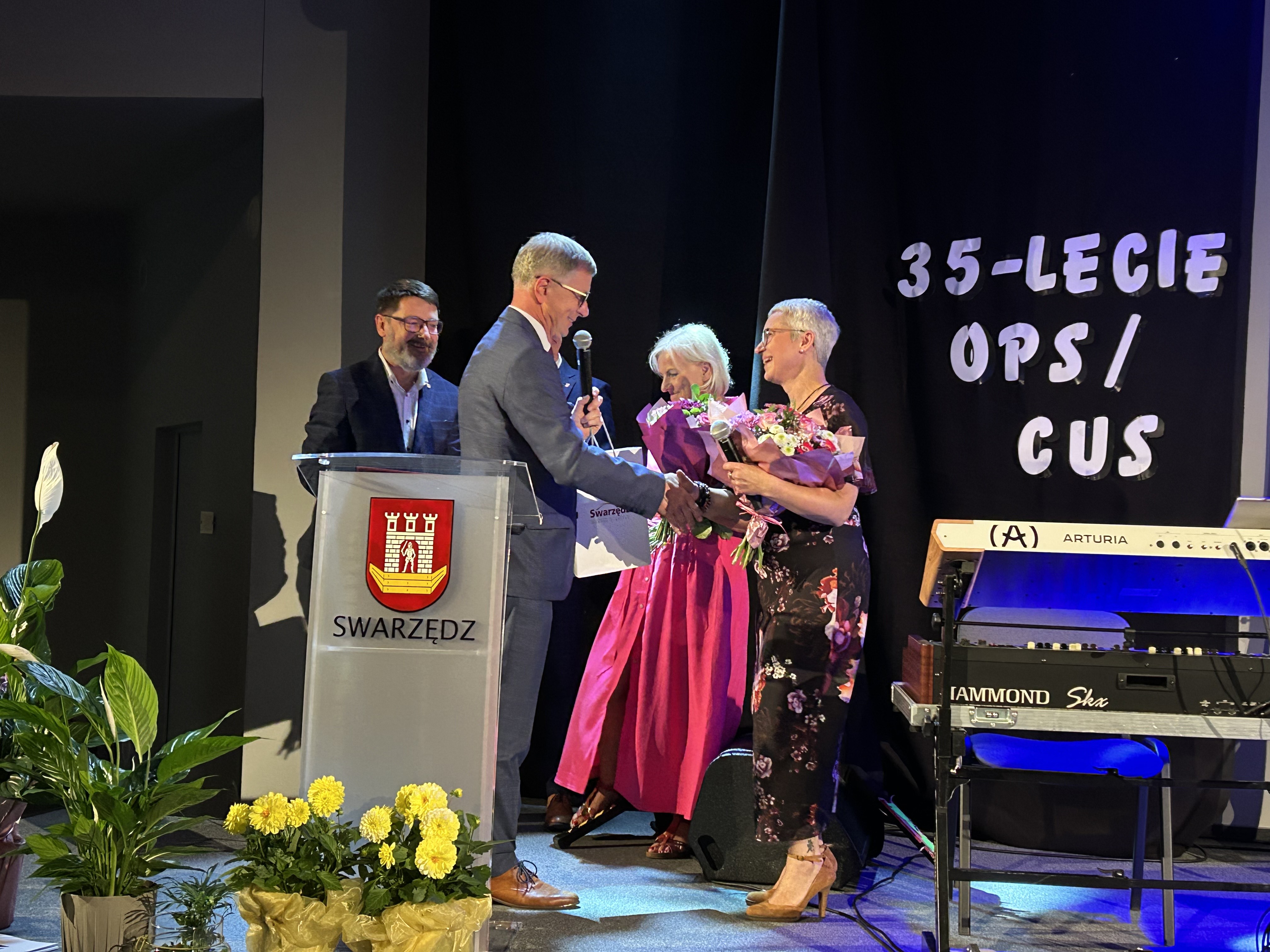 Obchody trzydziestopięciolecia Ośrodka Pomocy Społecznej i Centrum Usług Społecznych. Na scenie od prawej Dyrektor Centrum, burmistrz, przedstawicielki województwa wielkopolskiego, Rady Miejskiej w Swarzędzu i starostwa powiatowego.