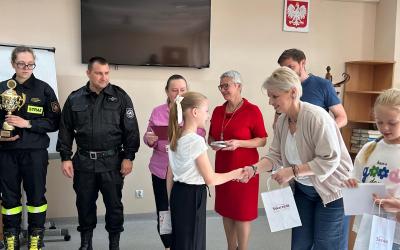 Zdjęcie ukazuje moment wręczenia nagrody i dyplomu jednej z zawodniczek przez dyrektor szkoły podstawowej numer dwa w Swarzędzu. Po prawej stronie dyrektor stoi troje przedstawicieli Centrum Usług Społecznych oraz dwoje strażaków.