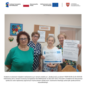 Wnętrze świetlicy wiejskiej w Paczkowie. Cztery seniorki pozują do zdjęcia trzymając plakaty projektowe.