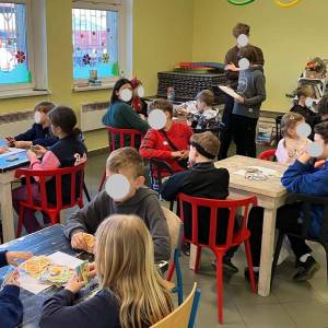 Zdjęcie przedstawia turniej gier planszowych dla dzieci w świetlicy wiejskiej w Gruszczynie. Przy pięciu różnych stolikach gra od trzech do czterech osób.