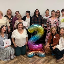 Na zdjęciu grupa uczestniczek Klubu Kobiet z nadmuchanym balonem - cyfrą 2 pozują do zdjęcia.