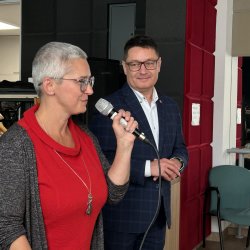 Konferencja pod tytułem Mosty Kultury. Do mikrofonu mówi Agnieszka Maciejowicz, dyrektor Centrum Usług Społecznych. Obok stoi drugi zastępca burmistrza.