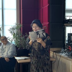 Poetka romska prezentuje swoją twórczość przed publicznością. Obok niej siedzi kobieta, jedna z prelegentek.