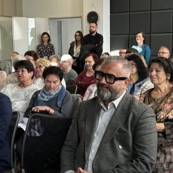 Zdjęcie przedstawia widok publiczności słuchającej wykładu.