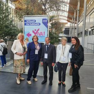 Zdjęcie przedstawia pięcioro uczestników gali konkursu viva seniorzy. Osoby ubrane uroczyście stoją pomiędzy budynkami Targów Poznańskich.