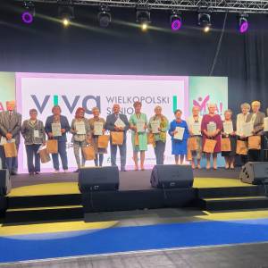 Na scenie stoi szesnaścioro laureatów tegorocznej edycji konkursu viva seniorzy. Po skrajnej lewej stronie sceny widać gości, którzy wręczali nagrody.