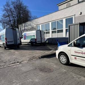 Zdjęcie przedstawia parking obok Centrum Usług Społecznych w Swarzędzu. Widać samochód służbowy Centrum, dwa busy służące do badań oraz budynek cusu.