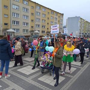 Marsz Kolorowej Skarpetki. Na zdjęciu widać kilkadziesiąt osób z balonami i transparentami, idących po deptaku na osiedlu Czwartaków.