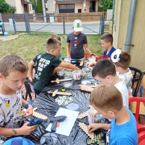Zdjęcie wykonano w trakcie półkolonii letnich. Warsztaty kreatywne na dworze, w których bierze udział ośmiu chłopców.