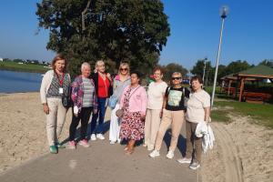 Grupa seniorek z Centrum Aktywności Seniora w Swarzędzu pozuje do wspólnego zdjęcia w czasie spaceru po promenadzie nadwarciańskiej w Śremie.