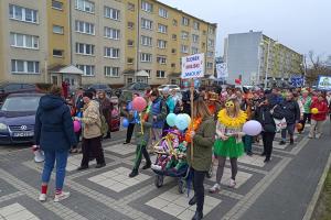 Marsz Kolorowej Skarpetki. Na zdjęciu widać kilkadziesiąt osób z balonami i transparentami, idących po deptaku na osiedlu Czwartaków.
