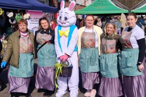 Zdjęcie przedstawia pięć członkiń Koła Gospodyń Wiejskich z zającem maskotką na terenie targowiska w Swarzędzu.
