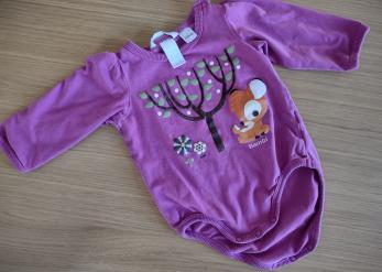  Body z długim rękawem w kolorze fioletowo-różowym, ozdobione nadrukiem drzewa i postacią Bambi, rozłożone na drewnianym stole.