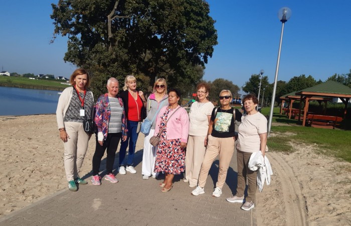 Grupa seniorek z Centrum Aktywności Seniora w Swarzędzu pozuje do wspólnego zdjęcia w czasie spaceru po promenadzie nadwarciańskiej w Śremie.