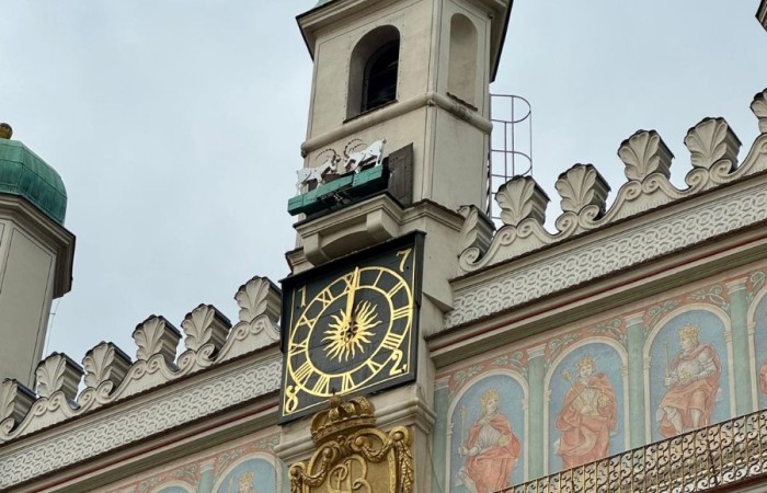 Ratusz Starego Miasta w Poznaniu. Zdjęcie wykonane w zbliżeniu przedstawia zegar i wieżę ratuszową z trykającymi się koziołkami.