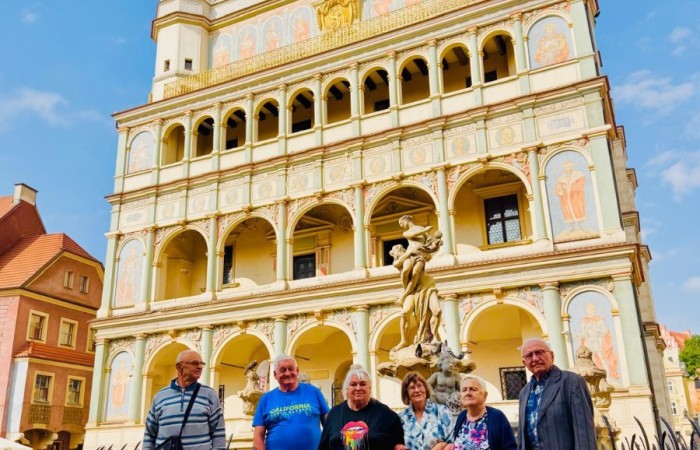 Grupa składająca się z trzech seniorek i trzech seniorów stoi przed zabytkową fasadą ratusza w Poznaniu.