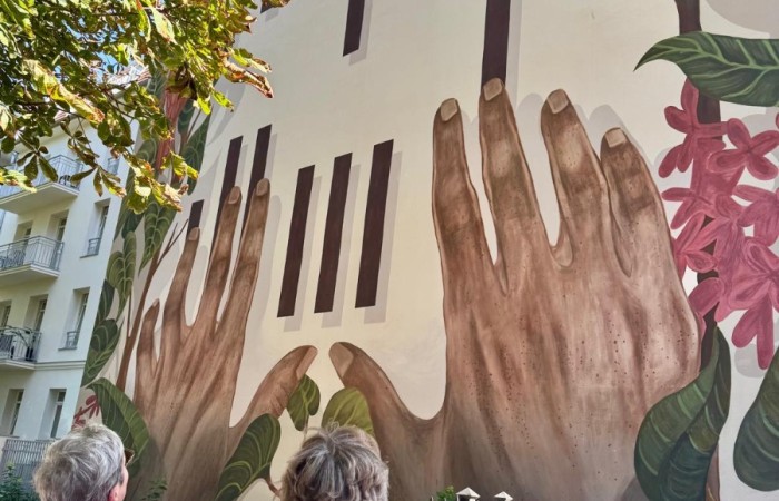 Zdjęcie przedstawia dwie seniorki podziwiające mural namalowany na jednej z poznańskich kamienic.