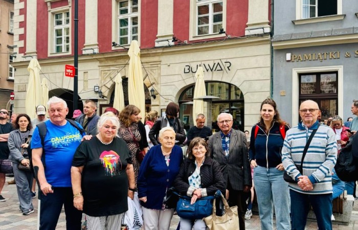Grupa seniorów i rehabilitantka z Dziennego Domu Senior Wigor stoją przed kawiarnią Bulwar w Poznaniu.