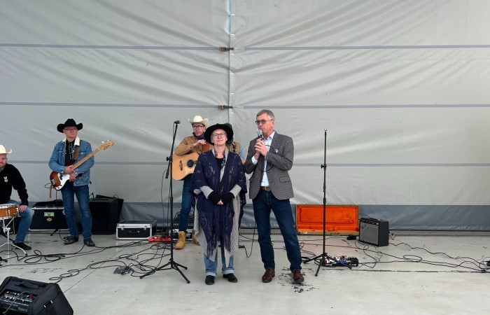 Zdjęcie przedstawia panią dyrektor Centrum Usług Społecznych w Swarzędzu i pana burmistrza przemawiających do zebranych na imprezie pod namiotem. Obok mówiących stroi zespół muzyczny ubrany w kowbojskie stroje.