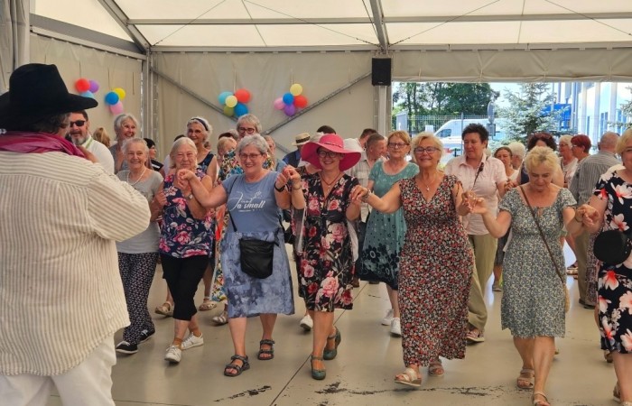 Na pierwszym planie widać seniorów, którzy tańczą uroczystego poloneza w towarzystwie Wiceburmistrza Tomasza Zwolińskiego i Dyrektor Centrum Usług Społecznych Agnieszki Maciejowicz. Taniec koordynuje wodzirej Kazimierz Hojna.