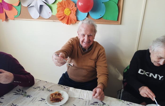 Zdjęcie ukazuje radość pana Antoniego, który znalazł w swoim kawałku ciastka fève, czyli małą porcelanową figurkę. Tym samym stał się pierwszym królem tego dnia. Pan Antoni siedzi przy stole, a na jego twarzy widać szczęście. Lewą rękę ma położoną na stole, a prawą, która trzyma łyżeczkę, wyciąga mocno przed siebie, tak żeby wszyscy zobaczyli figurkę.